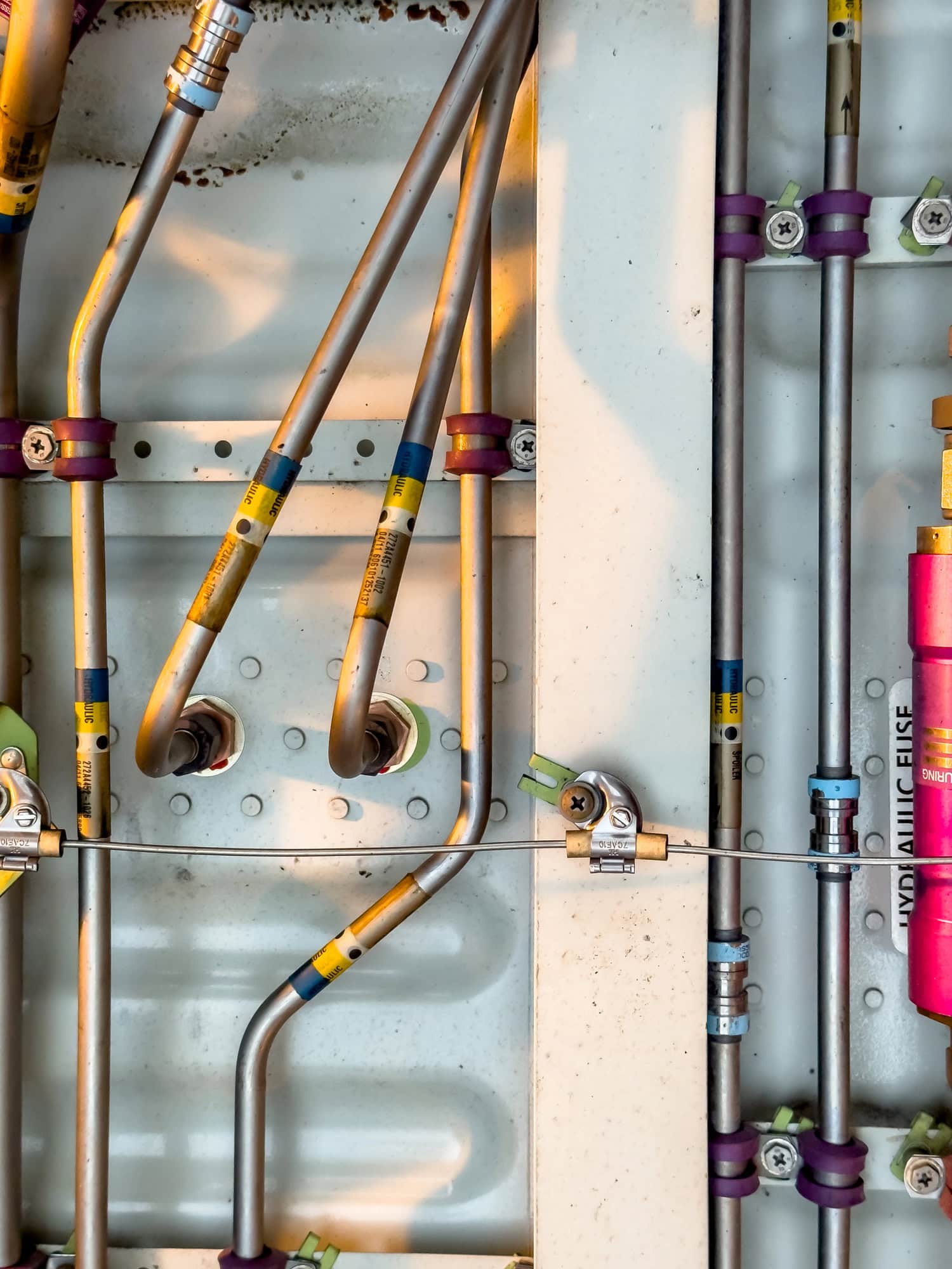 Detailed image of various pipes, hoses, tubes from the inside of an airplane. Hydraulic lines, valves, tubes, switches and wires in colourful arrangement.